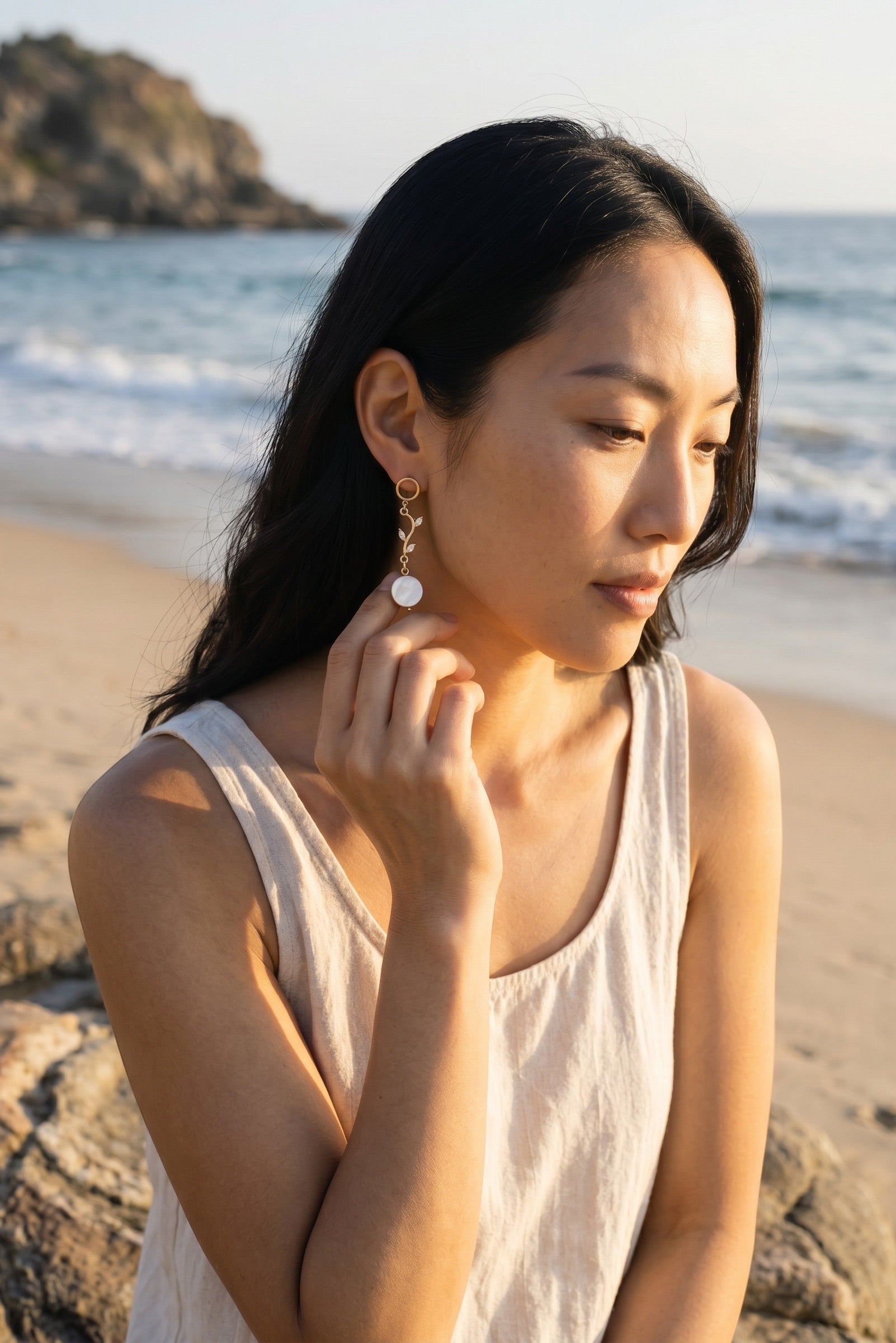 Sand and Sea 18k gold dangle earrings with white shell beads and leaf accents. Elegant coastal charm.