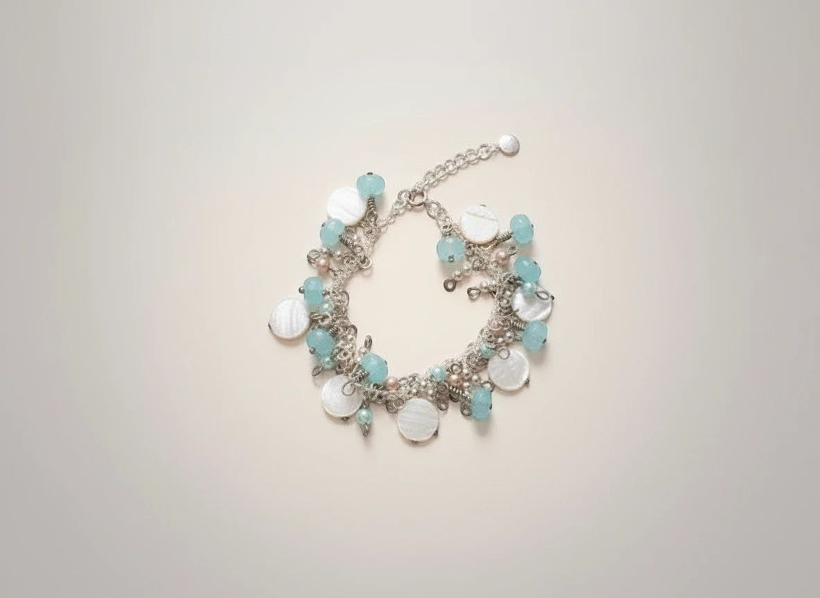 Sand and Sea handmade beach-inspired charm bracelet with white lentil shells, turquoise rondelles, and pearl beads.