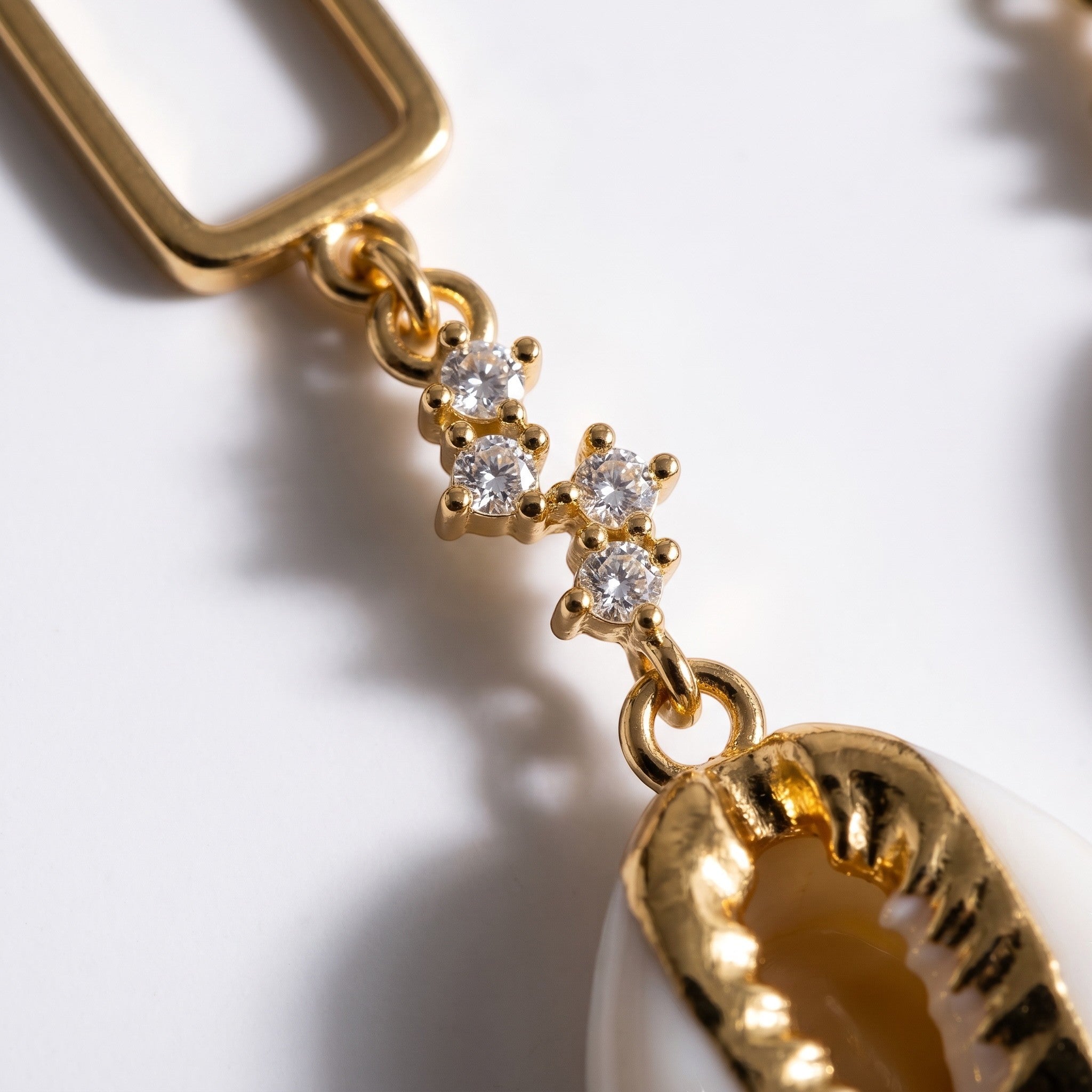 Sand and Sea gold-tone dangle earrings with cubic zirconia and cowrie shell pendant.