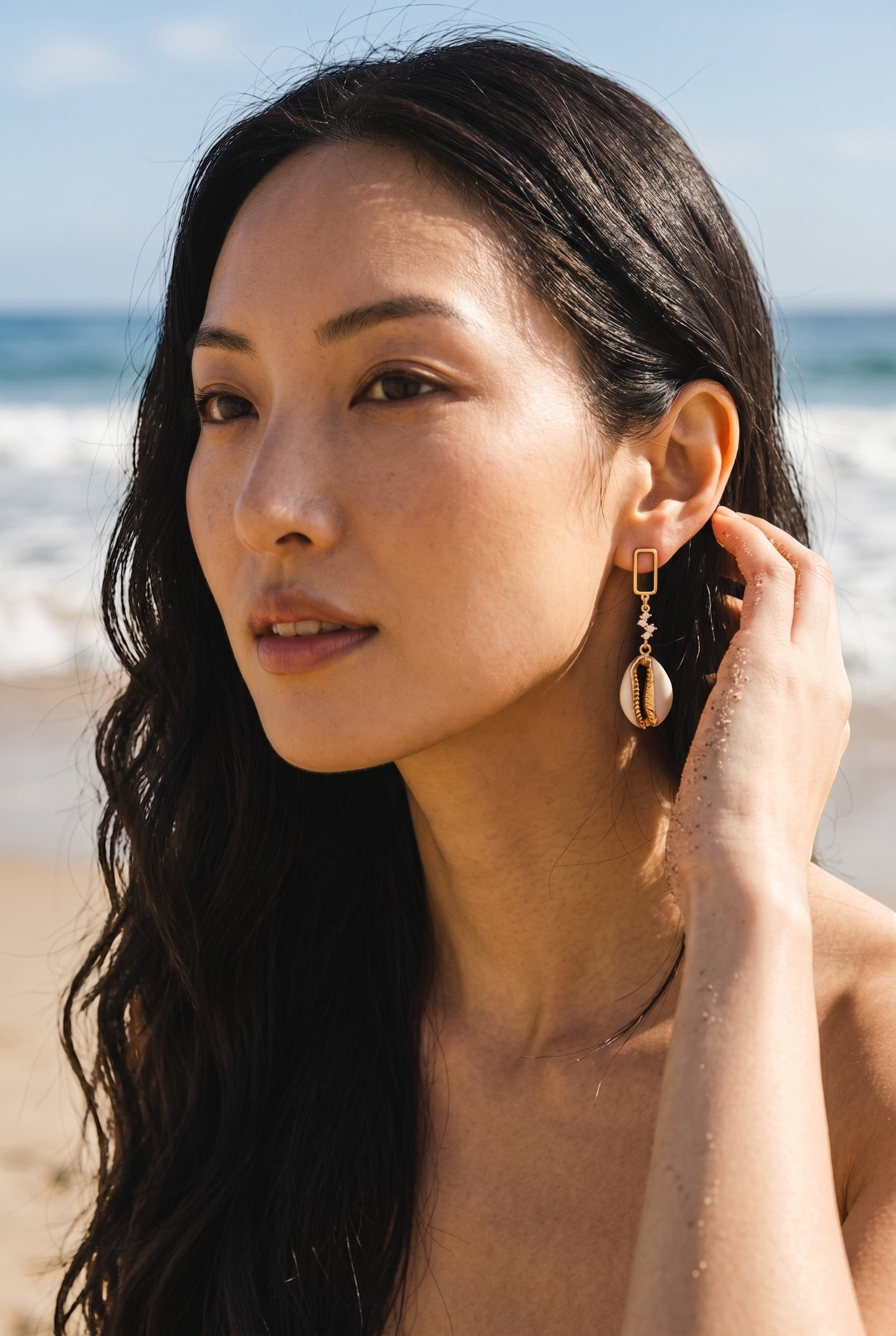 Sand and Sea gold-tone dangle earrings with cubic zirconia stud and natural cowrie shell pendant.