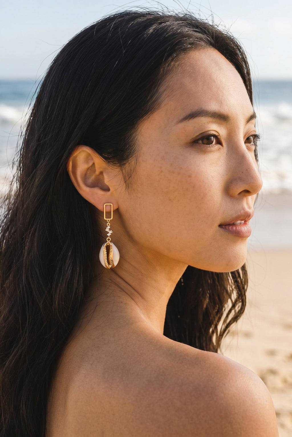 Sand and Sea gold-tone dangle earrings with cubic zirconia and cowrie shell pendant.