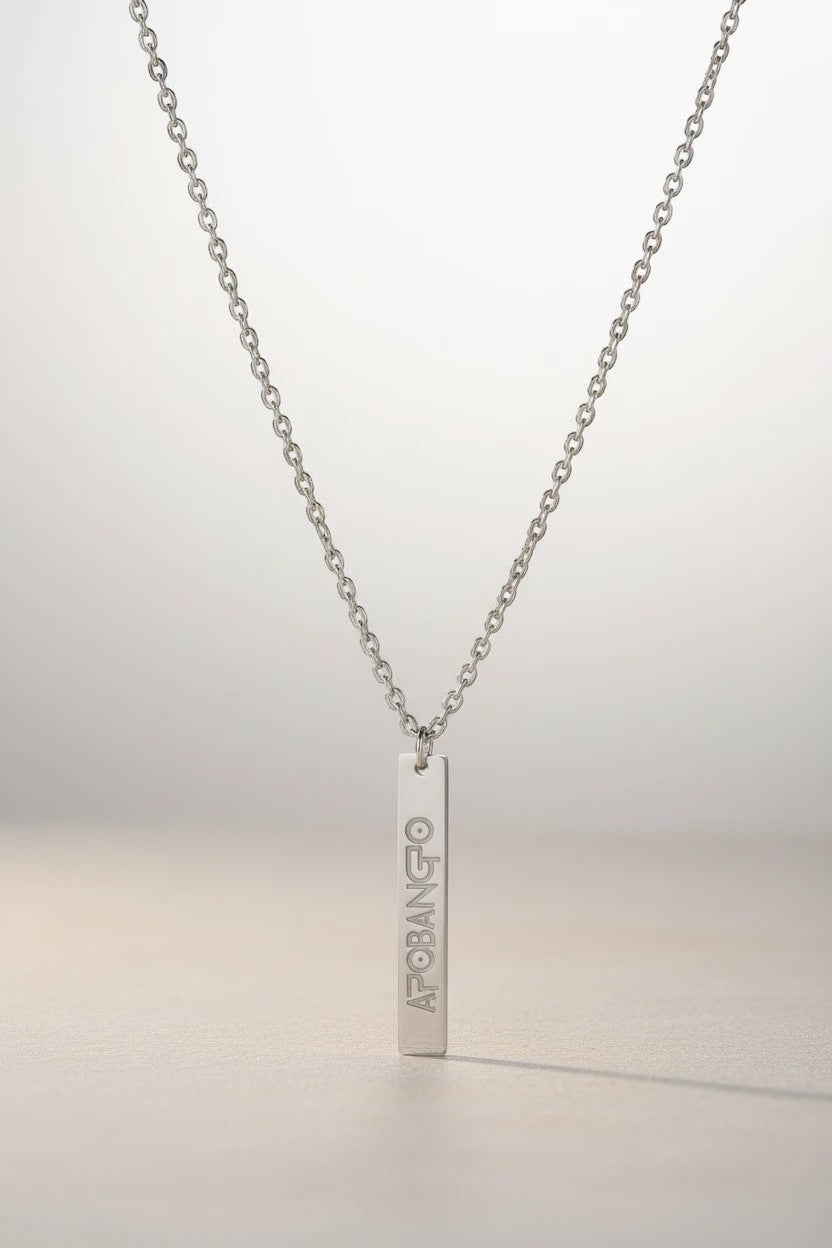 Sand and Sea engraved silver vertical bar necklace with "APOBANGO" text, made of stainless steel.