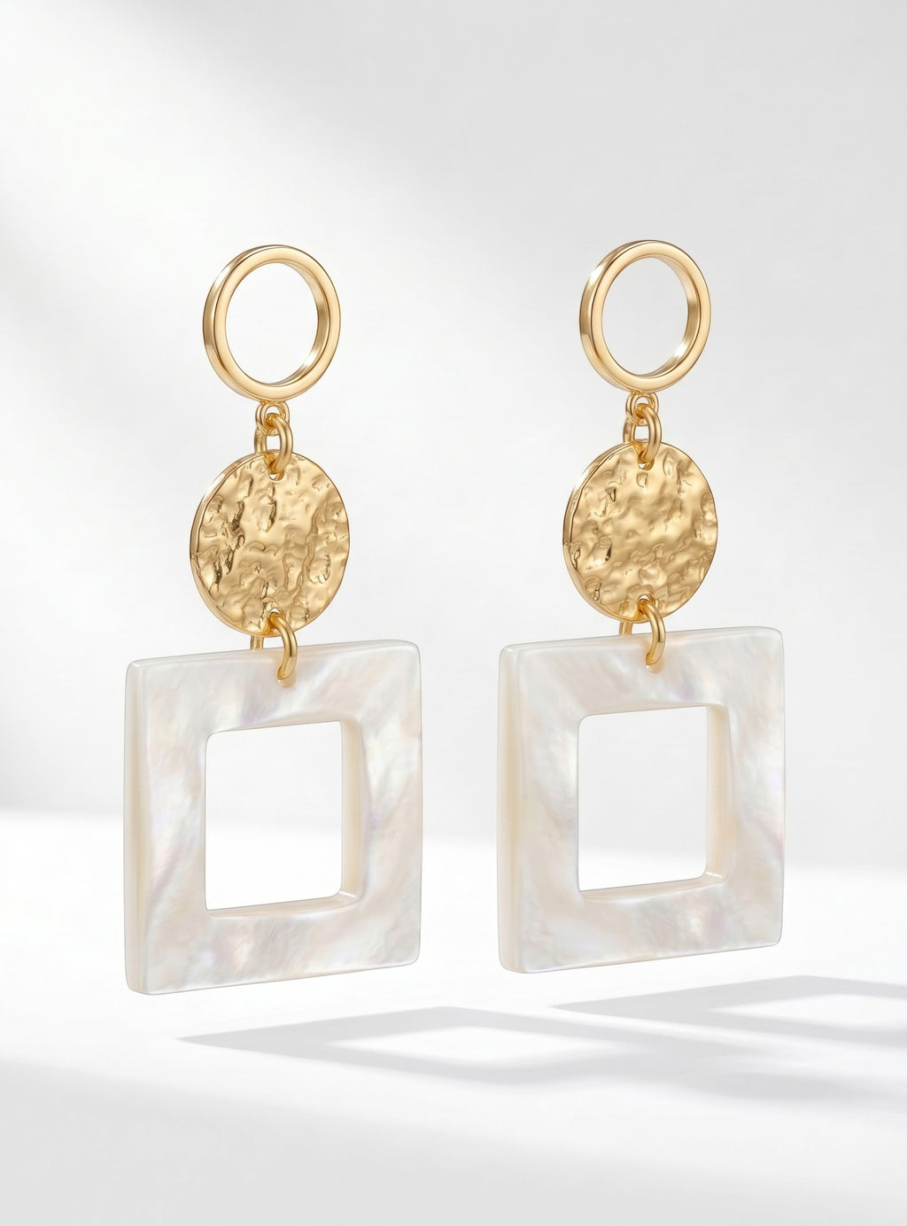 Sand and Sea geometric drop earrings with gold hoops, hammered gold discs, and matte white square pendants.