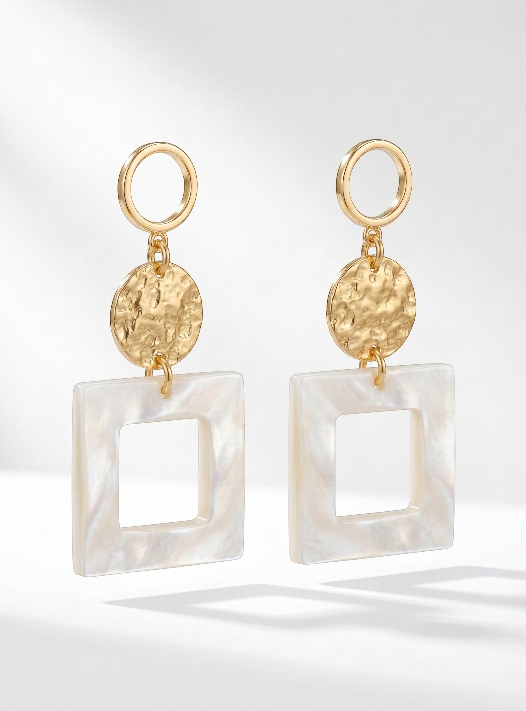 Sand and Sea geometric drop earrings with gold hoops, hammered gold discs, and matte white square pendants.