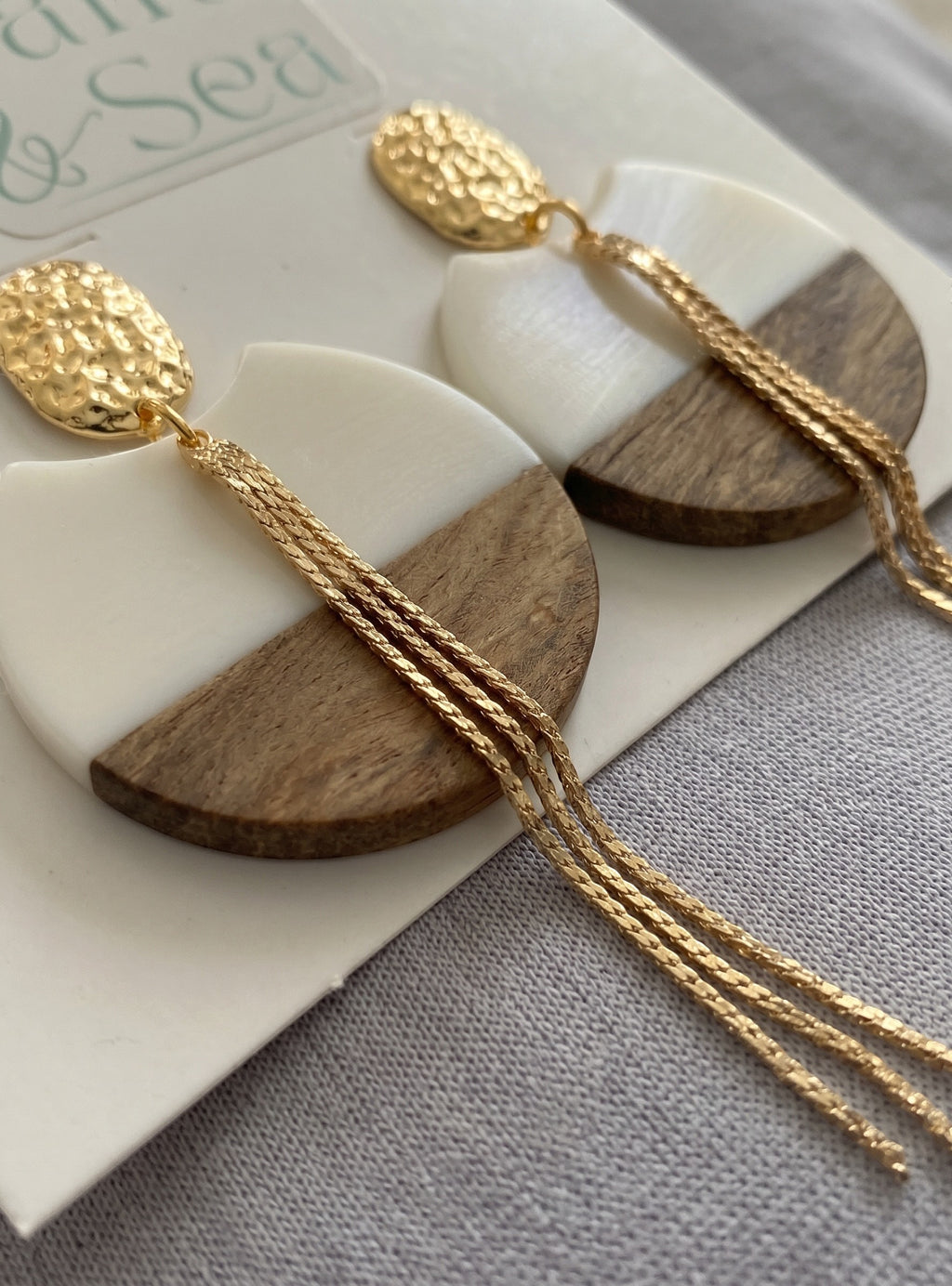 Sand and Sea geometric drop earrings with white resin and wood halves, gold chains, and hammered gold tops.