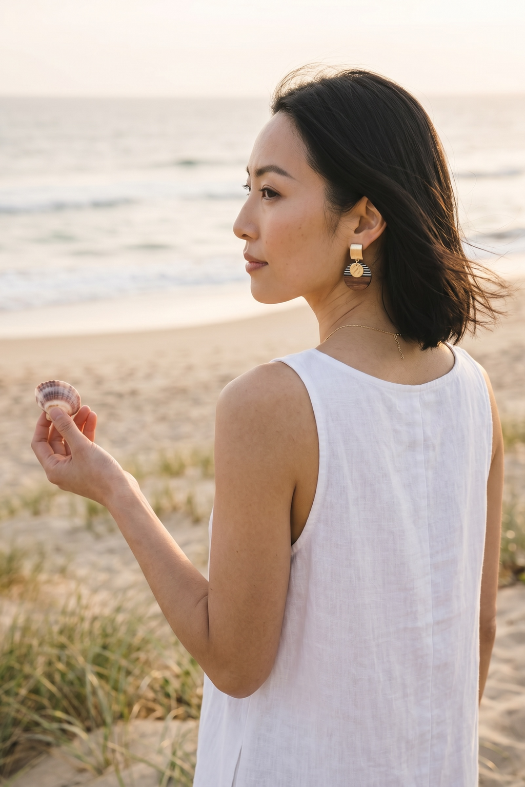 Sand and Sea geometric wood and stripe drop earrings with gold-tone accents on a woman at the beach.