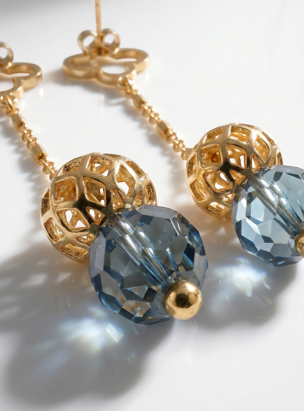 Sand and Sea gold-tone drop earrings with blue faceted gemstone beads and clover studs.