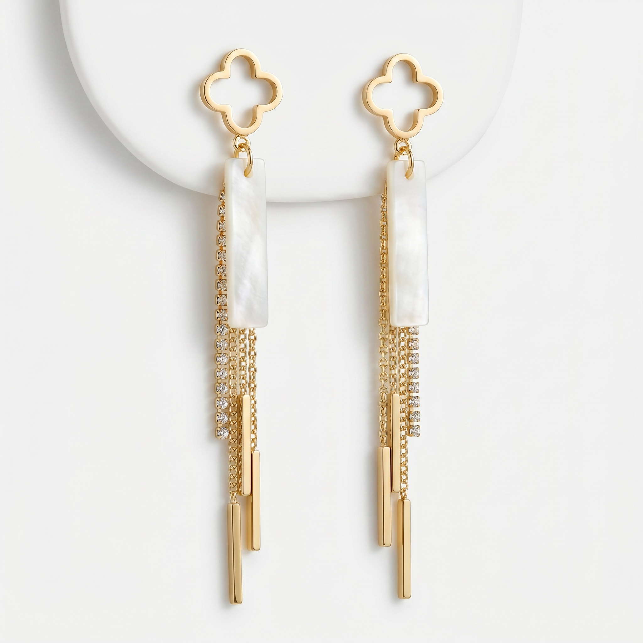 Sand and Sea gold clover dangle earrings with white stone inlay and crystal chain tassels.