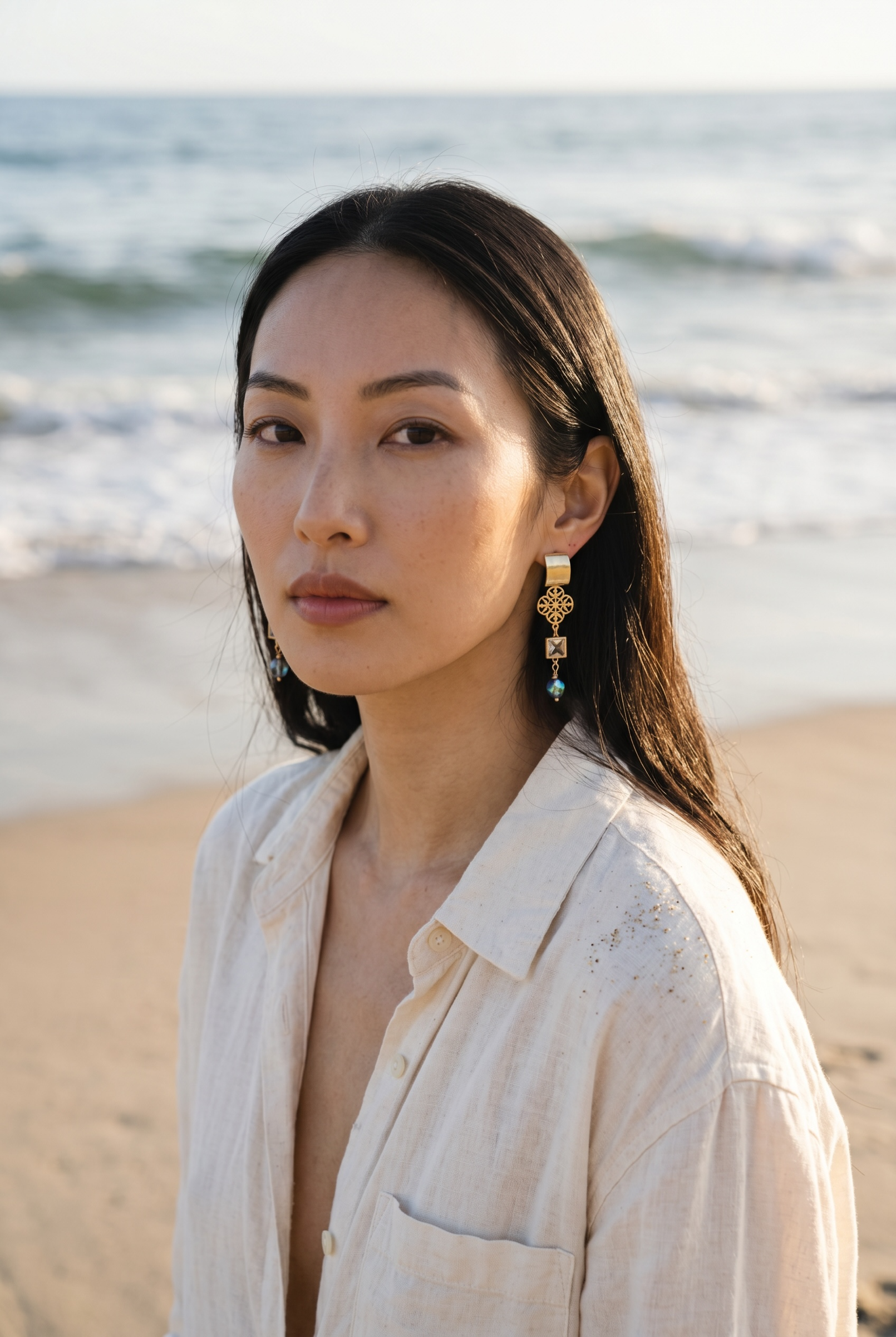 Sand and Sea gold-plated dangle earrings with quatrefoil charm, cubic zirconia, and blue-green teardrop bead.