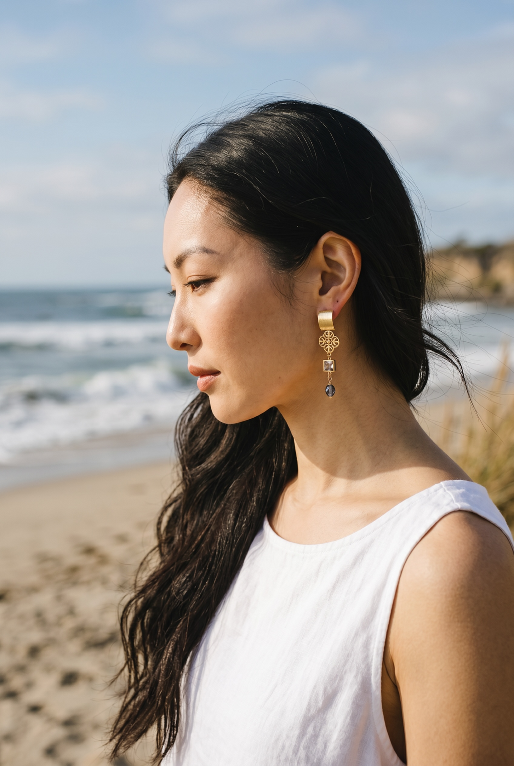 Sand and Sea gold-plated dangle earrings with quatrefoil charm, princess-cut cubic zirconia, and blue-green teardrop bead.