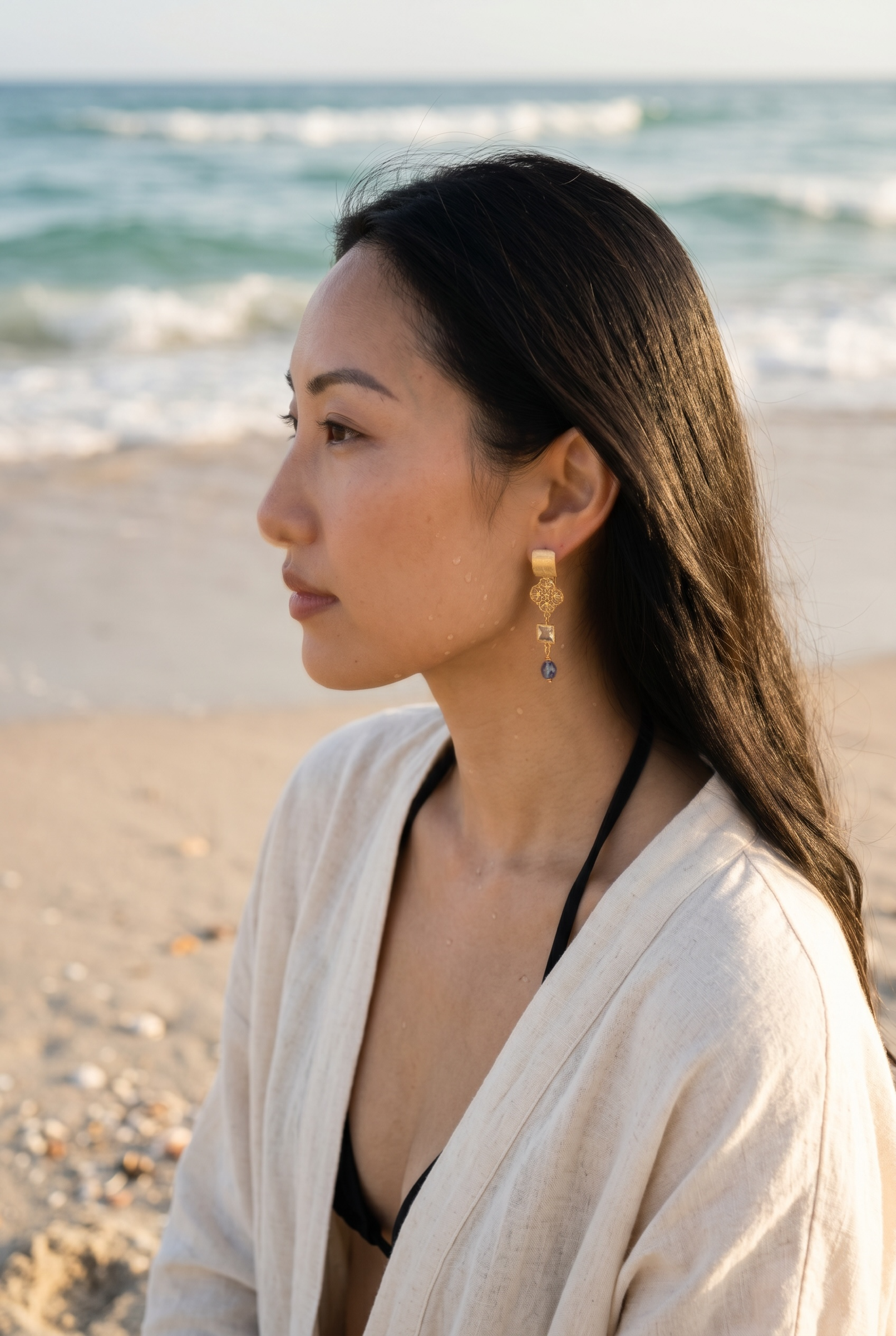 Sand and Sea gold-plated dangle earrings with filigree charm, cubic zirconia, and blue-green teardrop bead.