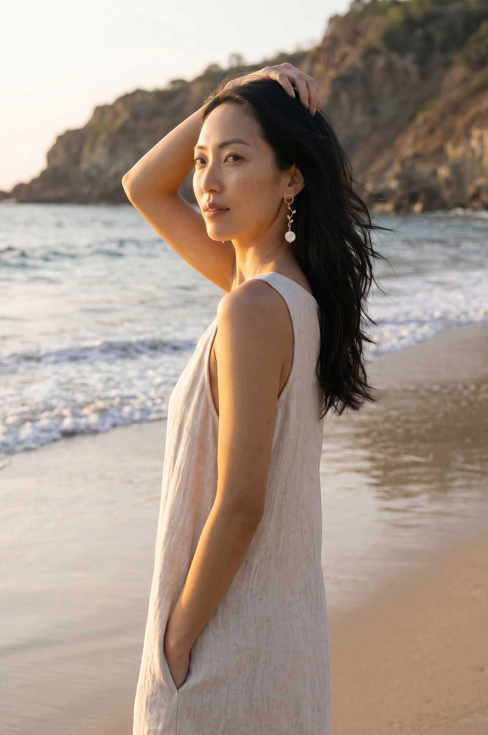Sand and Sea 18k gold dangle earrings with white shell beads and leaf accents, 3 inches long.