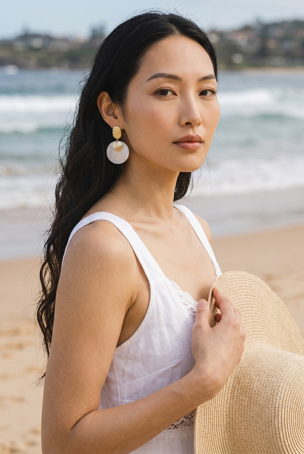 Sand and Sea round disc shell earrings with gold accent. Textured gold-tone metal top with iridescent shell disc.